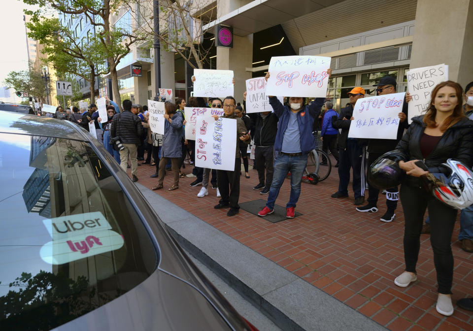 FILE - In this May 8, 2019, file photo, Uber and Lyft drivers carry signs during a demonstration outside of Uber headquarters in San Francisco. The ride-hailing companies Uber and Lyft say they are willing to change the way they treat drivers in California. That could include paying a base wage and providing certain benefits. But the companies are arguing they need to continue to classify drivers as independent contractors, not employees. California lawmakers are considering legislation that would tighten the rules around how companies classify workers as contractors. (AP Photo/Eric Risberg, File)