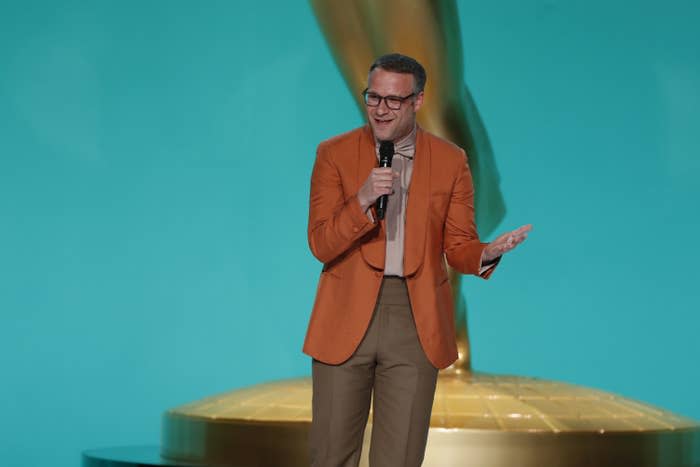 Seth Rogen talks on stage with a microphone in his hand