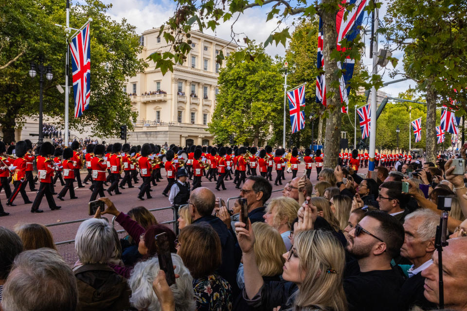 LONDON, ENGLAND - SEPTEMBER 14: Members of the public photograph the cortege carrying the coffin of Queen Elizabeth II  on September 14, 2022 in London, England. Queen Elizabeth II's coffin is taken in procession on a Gun Carriage of The King's Troop Royal Horse Artillery from Buckingham Palace to Westminster Hall where she will lay in state until the early morning of her funeral. Queen Elizabeth II died at Balmoral Castle in Scotland on September 8, 2022, and is succeeded by her eldest son, King Charles III. (Photo by Louise Delmotte/Getty Images)