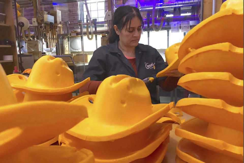 This Jan. 13, 2020 photo shows Maria Hernandez trimming foam cowboy hats at Foamation, Inc. in Milwaukee. Ralph Bruno invented the yellow wedge cheesehead in 1987 from his mother's couch stuffing and it has since become popular, particularly for Wisconsin sports fans and residents. His company, Foamation, Inc., which makes other foam products like these cowboy hats, moved into a new location in 2016 and soon started tours where people can make their own cheeseheads or other foam products. (AP Photo/Carrie Antlfinger)