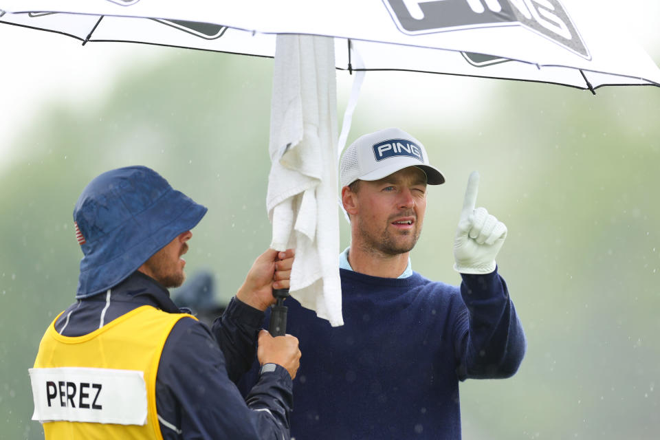 Victor Perez talks to his caddie under an umbrella