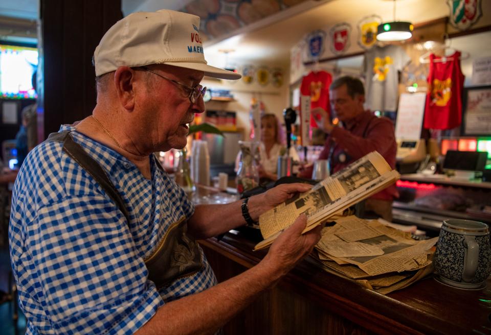 Tom Memmer III flips through old newspaper clippings about Volkfest over the years at Germania Maennerchor’s Rathskeller Thursday, July 27, 2023.