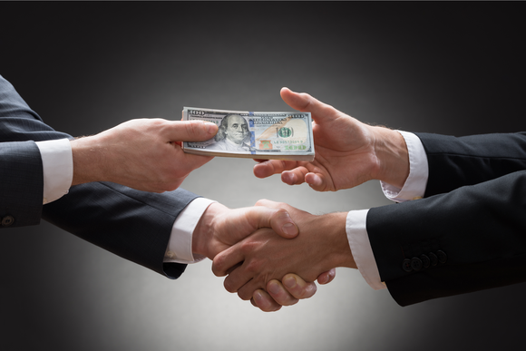 Businessmen shaking hands and exchanging money