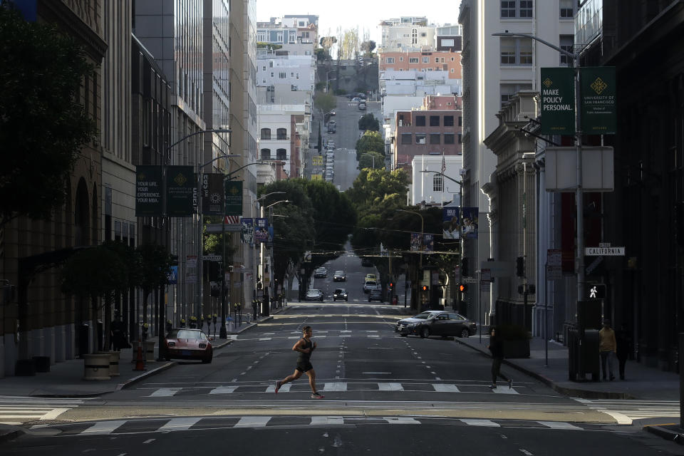 A man runs across a near empty Montgomery Street in San Francisco, March 21, 2020. (AP Photo/Jeff Chiu)