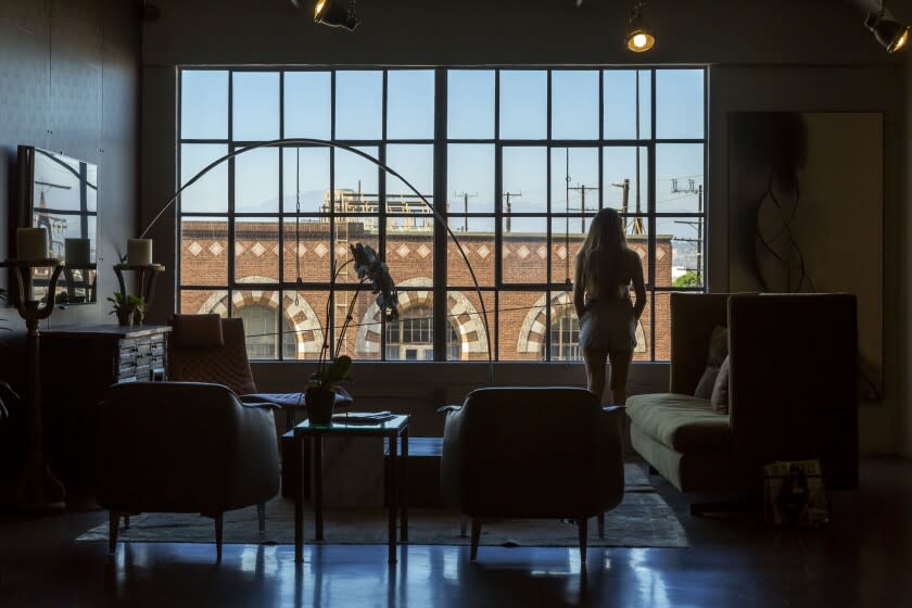 LOS ANGELES, CA - AUGUST 18, 2016 - Denise and Ron Meraz' loft in a repurposed 1924 Toy Factory building downtown Los Angeles, August 18, 2016. Daughter Stephanie looking out the window with a view of downtown. What marks this loft is its warmth, which comes from the architect's juxtaposition of vintage and Old World touches within the industrial environment. The architect is Andrea Michaelson, and she originally designed this loft as a downtown pied-a-terre for her brother-in-law, who lives in Riverside. He since sold it to Denise and Ron. (Ricardo DeAratanha/Los Angeles Times).