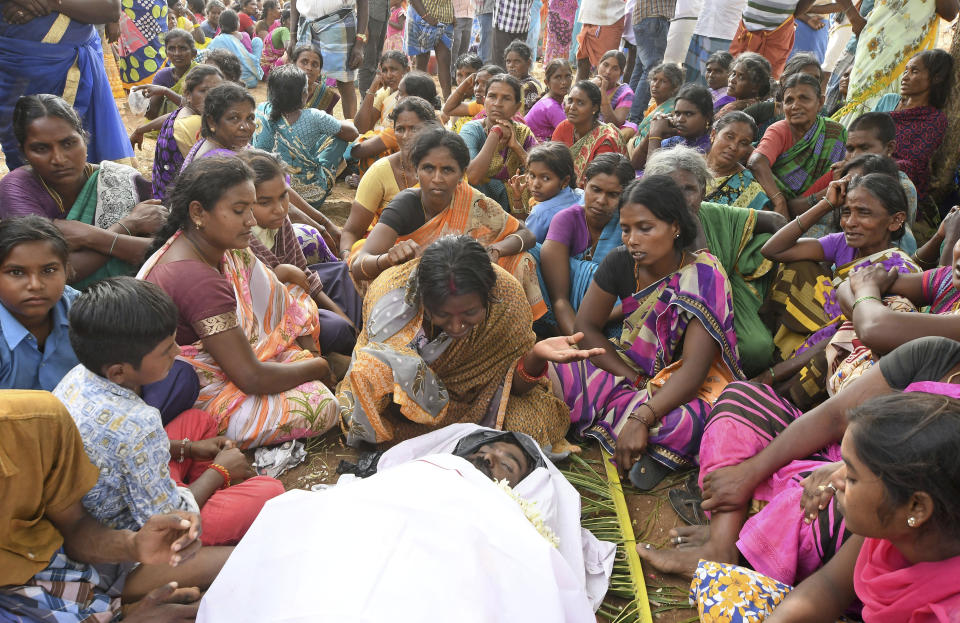 A woman cries near the body of her husband who died of suspected food poisoning at Bidarahalli, near Sulawadi village in Chamarajnagar district of Karnataka state, India, Saturday, Dec. 15, 2018. Police on Saturday arrested three people after at least 10 died of suspected food poisoning following a ceremony to celebrate the construction of a new Hindu temple in southern India. (AP Photo/Madhusudhan Sr)