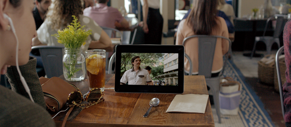 Woman in a restaurant watching Netflix on a tablet