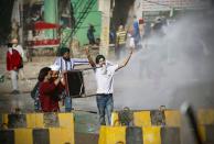 Protesting farmers react as tear gas shells explode at the border between Delhi and Haryana state, Friday, Nov. 27, 2020. Thousands of agitating farmers in India faced tear gas and baton charge from police on Friday after they resumed their march to the capital against new farming laws that they fear will give more power to corporations and reduce their earnings. While trying to march towards New Delhi, the farmers, using their tractors, cleared concrete blockades, walls of shipping containers and horizontally parked trucks after police had set them up as barricades and dug trenches on highways to block roads leading to the capital. (AP Photo/Manish Swarup)