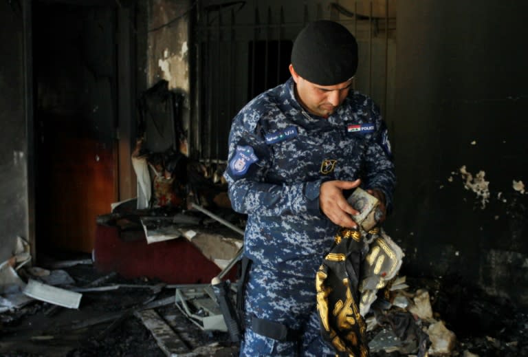 An Iraqi policeman holds a recovered holy Koran from the premises of the Islamic Dawa Party that was torched during protests in the central shrine city of Najaf on July 14, 2018