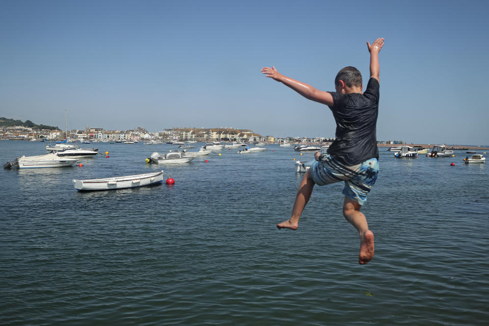 A boy jumps off a jetty into the Teign estuary in Shaldon, Devon, England, Wednesday July 21, 2021. Visiting the fishing village of Shaldon a small cluster of mainly Georgian houses and shops at the mouth of the River Teign, is like stepping back into a bygone era. It features simple pleasures that hark back to analog, unplugged summer days: a book and a picnic blanket, a bucket and spade, fish and chips. (AP Photo/Tony Hicks)