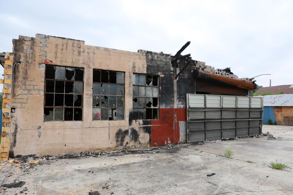 The burned remains of buildings with broken windows and unsecured openings remain across from Scissortail Park. The property caught fire in November 2022.