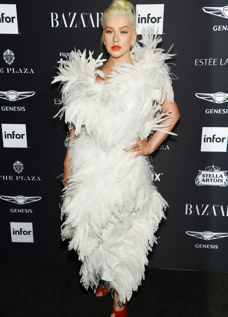 <p> This one might give you a little deja vu, as it's not the first time the pop star has sported a statement feathered look. For the Bazaar Icons party in 2018, Christina wore a Vivienne Westwood dress which was covered head to toe in white feathers. She paired the eye-catching dress with a bold coral lip and matching red shoes. </p>