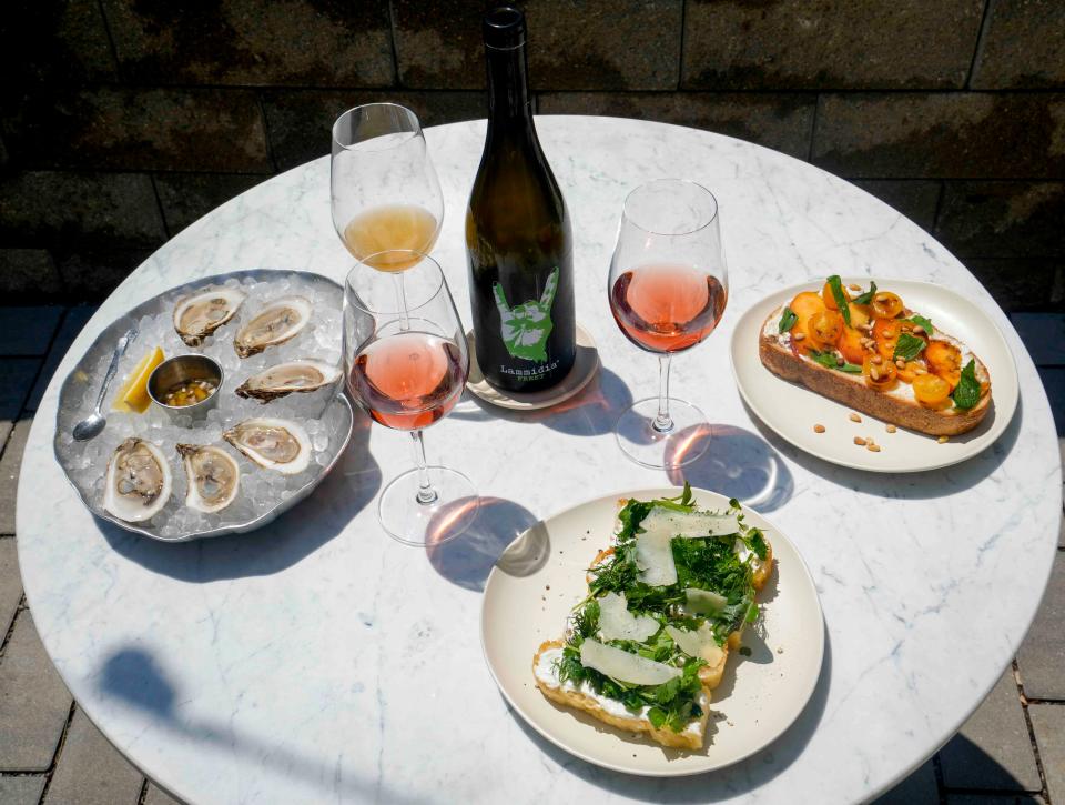 Offerings from Nonfiction Natural Wines include a half dozen BeauSoleil oysters with peach, honey and mint mignonette, clockwise from left; the Summer Toast topped with Georgia peaches, Sungold tomatoes, whipped mascarpone and feta, mint balsamic and pine nuts; and house-made focaccia topped with whipped ricotta, a soft herb salad, parmesan and lemon; plus a white Lammidia Frekt and Meinklang Prosa, a sparkling rose, seen at Nonfiction Natural Wines on July 8, 2023.