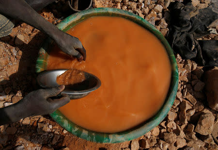 An artisanal miner pans for gold using a plastic wash basin and metal pan at an unlicensed mine near the city of Doropo, Ivory Coast, February 13, 2018. REUTERS/Luc Gnago