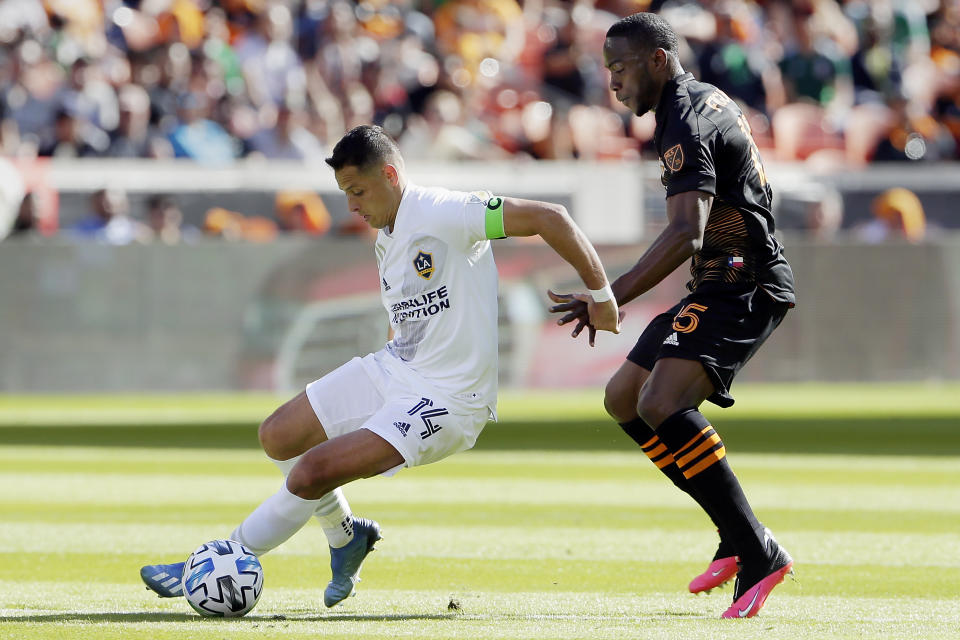 Los Angeles Galaxy forward Javier "Chicharito" Hernandez (14) moves the ball past Houston Dynamo defender Maynor Figueroa (15) during the first half of an MLS soccer match Saturday, Feb. 29, 2020, in Houston. (AP Photo/Michael Wyke)
