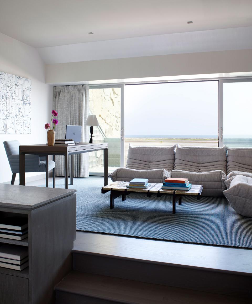 An office with a view: When duty calls, Moon’s clients work at this walnut-and-leather desk from Troscan. The low quilted sectional is from Michel Ducaroy’s Togo line, a Ligne Roset classic, and the ceramic coffee table is a vintage piece by Roger Capron.