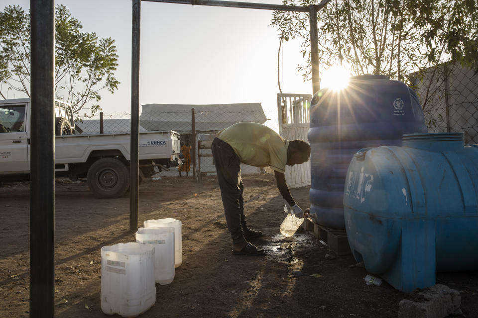 Surgeon and doctor-turned-refugee, Dr. Tewodros Tefera, fills a container with clean water to sanitize medical equipment, at the Sudanese Red Crescent clinic at the Hamdayet Transition Center near the Sudan-Ethiopia border, eastern Sudan, on March 22, 2021. With no running water or electricity, he and a handful of colleagues see well over 100 patients a day. (AP Photo/Nariman El-Mofty)