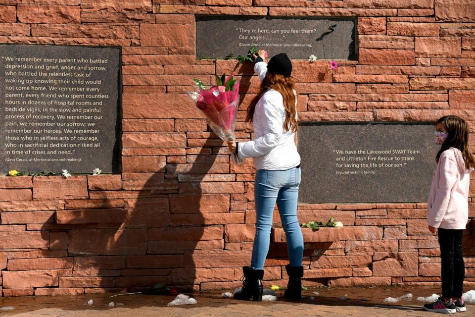 PHOTO: Brandy Munoz and her daughter Jazzy, leave flowers under placards with quotes at the Columbine Memorial at Robert F. Clement Park, Apr. 20, 2021, in Littleton, Colorado.  (Helen H. Richardson//Denver Post via Getty Images)