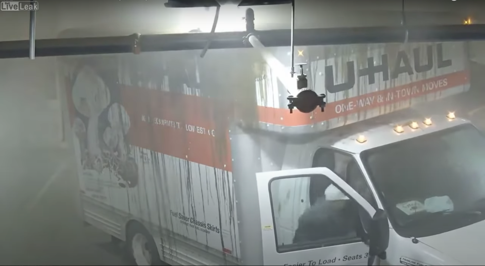 a photo of a U-Haul truck stuck in a parking garage with brown liquid all over its top and sides