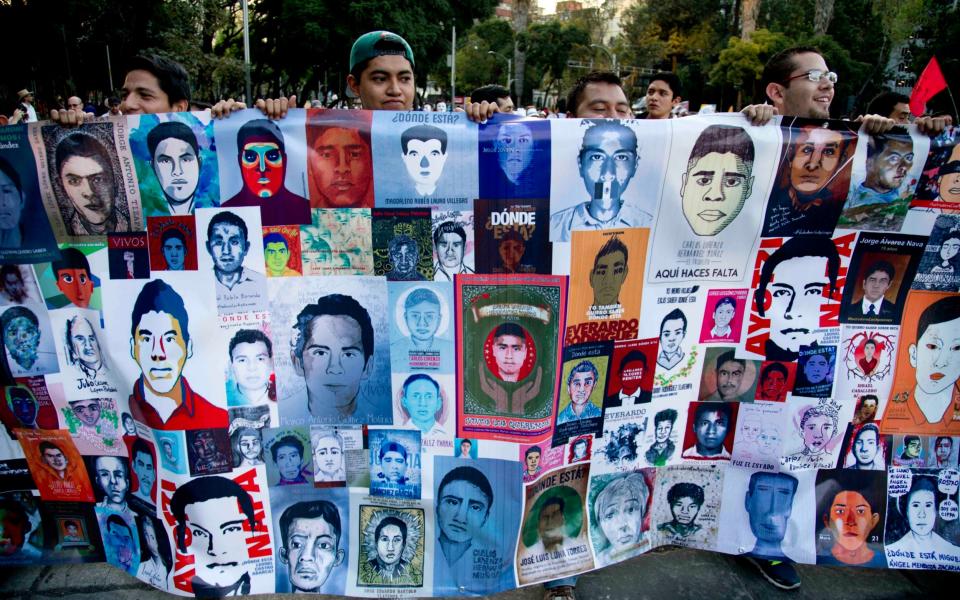 Demonstrators march holding images of missing students in protest for the disappearance of 43 students - Credit: AP Photo/Eduardo Verdugo
