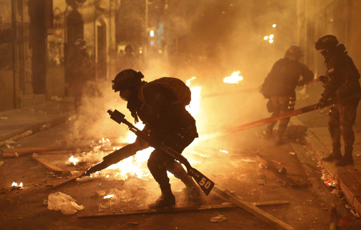 Police dismantle a burning barricade during a protest against the reelection of President Evo Morales, in La Paz, Bolivia, Thursday, Nov. 7, 2019. The United Nations on Thursday urged Bolivia's government and opposition to restore "dialogue and peace" after a third person was killed in street clashes that erupted after a disputed presidential election on Oct. 20. (AP Photo/Juan Karita)