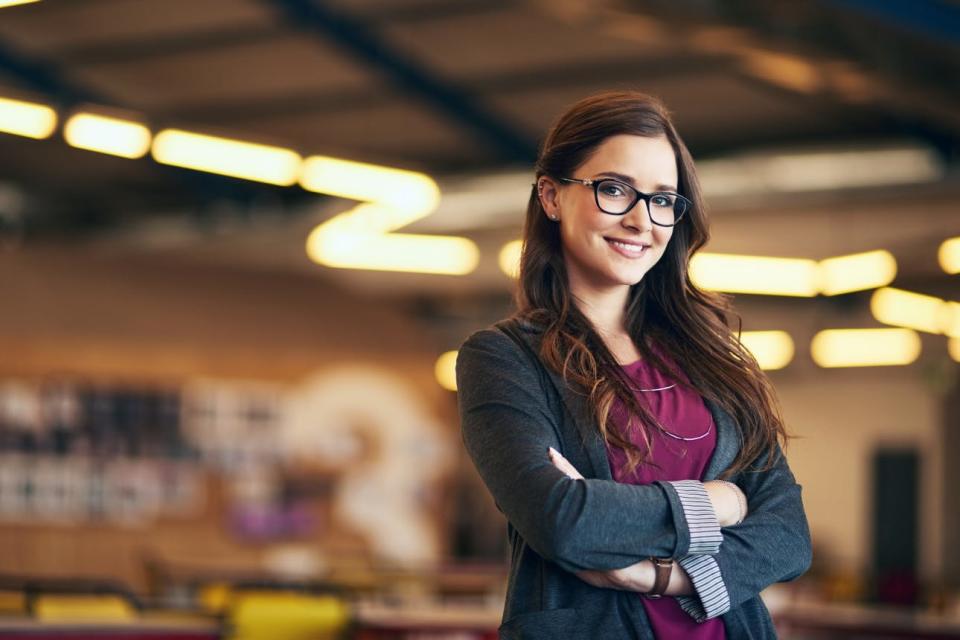 A confident woman wearing a blazer crosses her arms