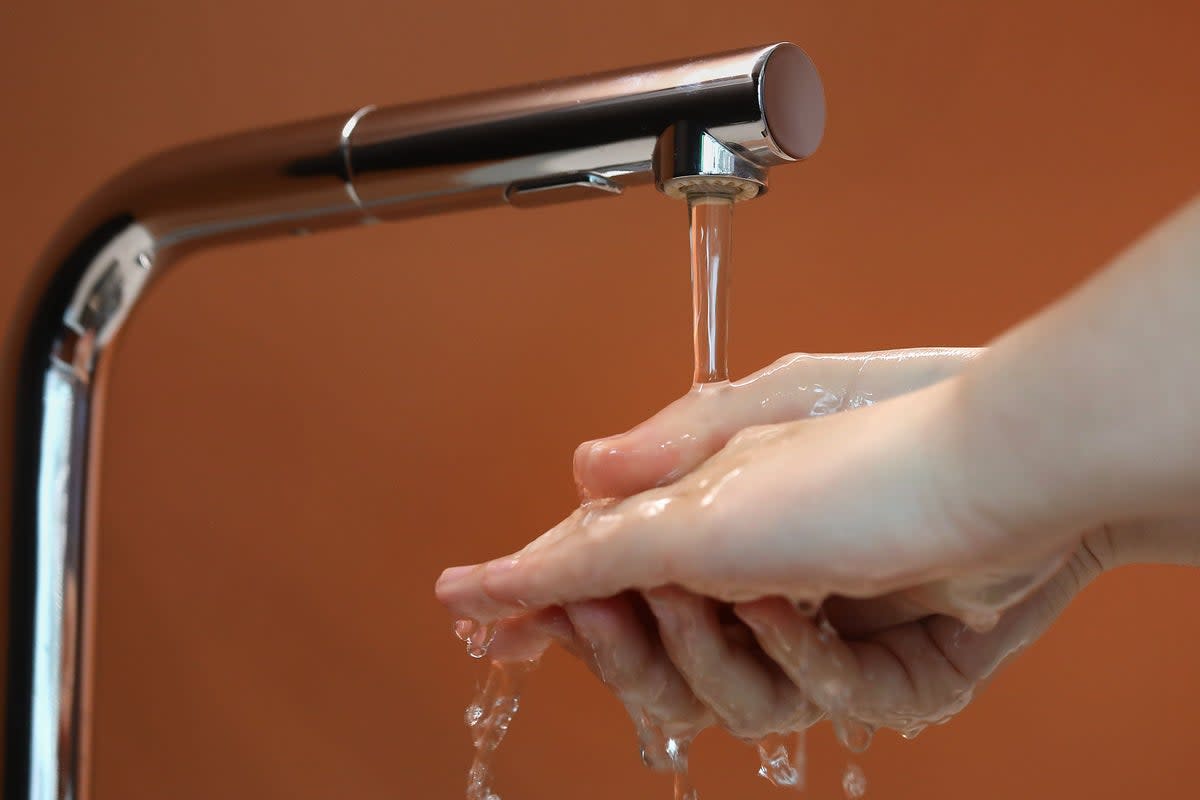 A person washes their hands under a tap (PA Archive)