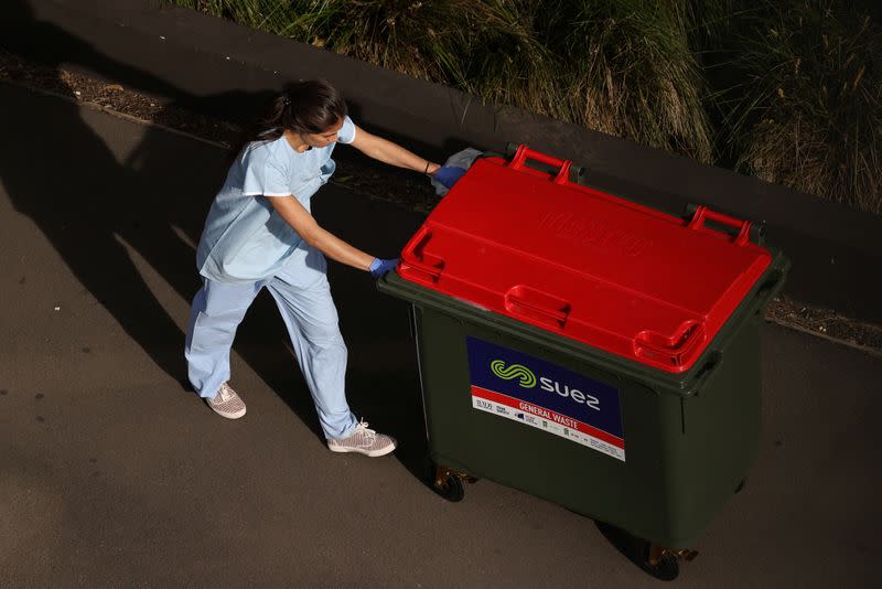 A worker disposes of waste outside a quarantine hotel in Sydney