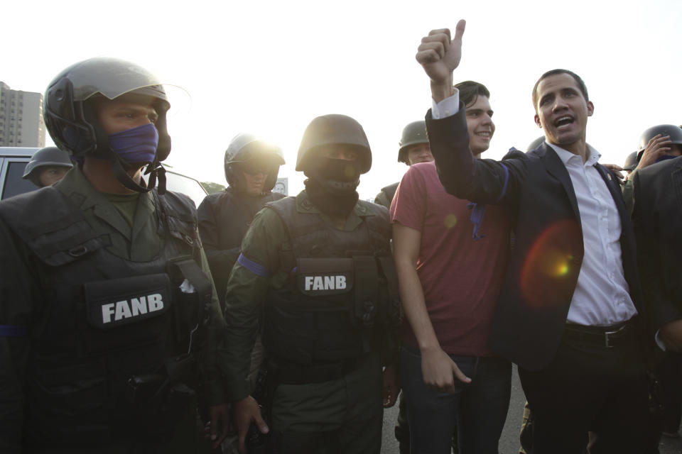 Venezuela's opposition leader and self proclaimed president Juan Guaido gestures next to soldiers outside La Carlota air base in Caracas, Venezuela, Tuesday, April 30, 2019. Guaido called for a military uprising, in a video shot at a Caracas air base showing him surrounded by soldiers and accompanied by detained activist Leopoldo Lopez. (AP Photo/Boris Vergara)