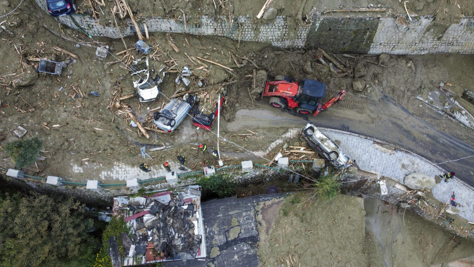 A caterpillar removes mud and debris after heavy rainfall triggered landslides that collapsed buildings and left as many as 12 people missing, in Casamicciola, on the southern Italian island of Ischia, Sunday, Nov. 27, 2022. Authorities said that the landslide that early Saturday destroyed buildings and swept parked cars into the sea left one person dead and 12 missing. (AP Photo/Salvatore Laporta)