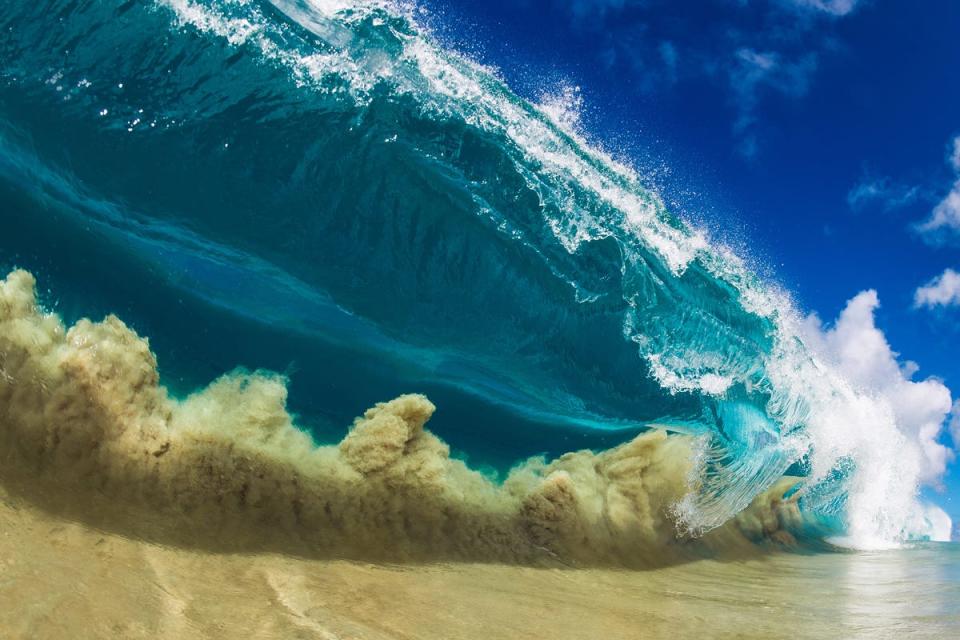 This image is called "Knock out." When large swells hit shallow sandbars, the sand on the seafloor can be pulled up into the face of the wave creating interesting cloud-like patterns. In the next moment, Clark will dive through the thick wall just in time to escape.