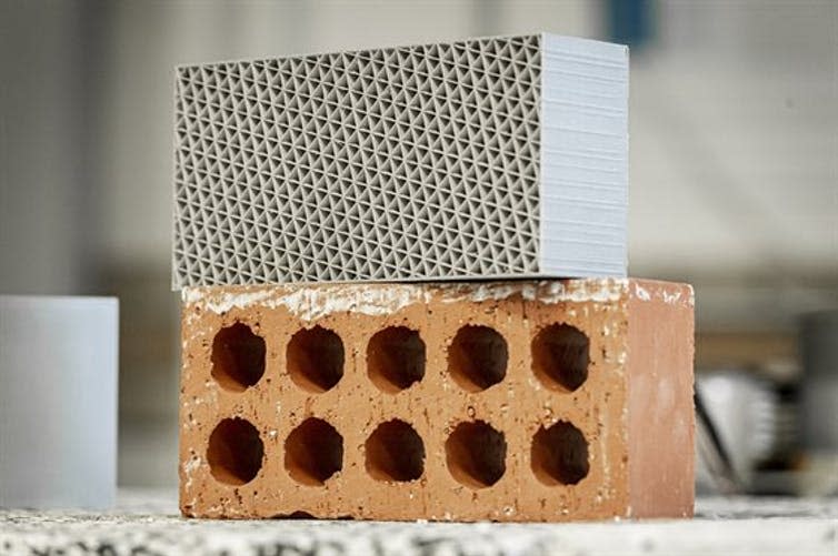 A 3D-printed plastic brick sits atop a a clay brick