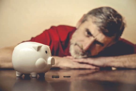 Senior man looking at a piggy bank