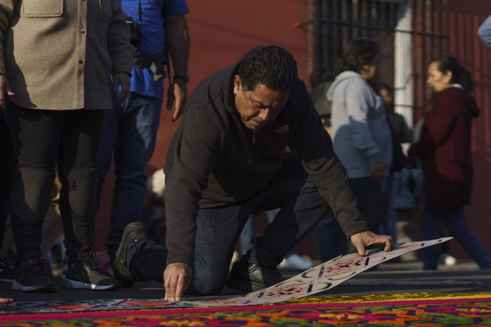 Luis Alvarez adds the finishing touches to his family's sawdust carpet in preparation for a Holy Week procession in Antigua, Guatemala, on Good Friday, March 29, 2024. (AP Photo/Moises Castillo)