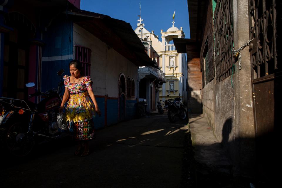 A woman walks past a Catholic church in La Ceiba, Guatemala.