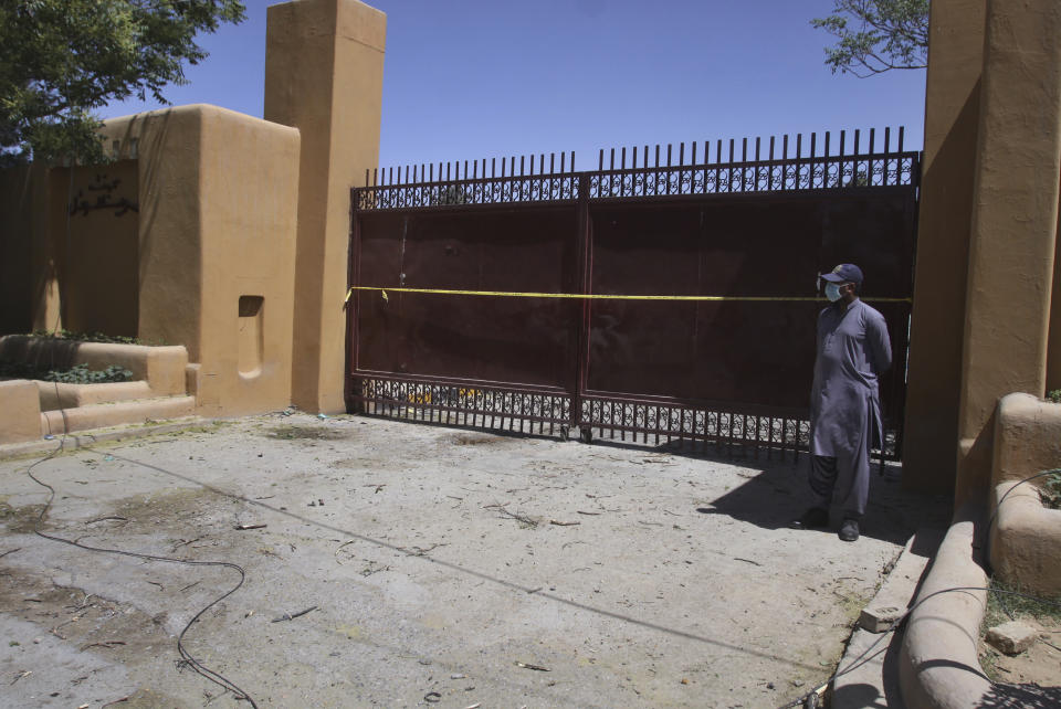 A private security guard stands at a closed entry gate of a luxury hotel that was the site of Wednesday's bomb blast, in Quetta, Pakistan, Thursday, April 22, 2021. An attack at a luxury hotel in Pakistan has been confirmed as a suicide car bombing, and the death toll has risen to five, police said Thursday. (AP Photo/Arshad Butt)