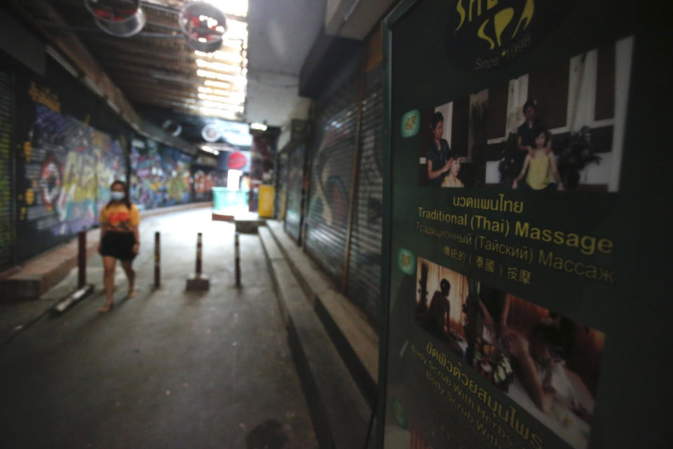 A passerby wearing a face mask to help curb the spread of the coronavirus moves past a closed massage shop in Khao San road, a popular hangout for Thais and tourists in Bangkok, Thailand, Monday, April 26, 2021. Cinemas, parks and gyms were among venues closed in Bangkok as Thailand sees its worst surge of the pandemic. A shortage of hospital beds, along with a failure to secure adequate coronavirus vaccine supplies, have pushed the government into imposing the new restrictions. (AP Photo/Anuthep Cheysakron)