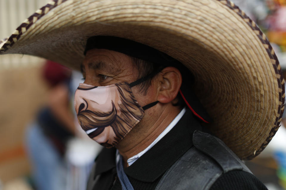 A man wearing a face mask walks amidst outdoor stalls at Mercado Sonora, which reopened ten days ago with measures to reduce congestion and limit the spread of the coronavirus, in Mexico City, Thursday, June 25, 2020. (AP Photo/Rebecca Blackwell)