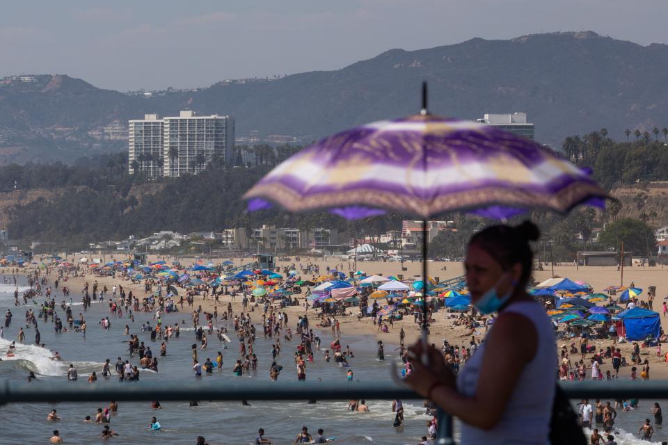 A woman uses an umbrella to protect herself from the sun at Santa Monica pier while people flocked to the beach amid a heat wave on Sept. 6, 2020. (Photo: Apu GOMES / AFP)