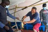 Waly Sarr, 30, right, Ibrahima Mbaye, 41, left, both from Senegal, and Salvatore Di Battista work on the deck of the "Vincenzo Padre" fishing boat where they work as fishermen, in the Island of Lampedusa, southern Italy, Thursday, May 13, 2021. The tiny island of Lampedusa, which is closer to Africa than the Italian mainland, is in the throes of yet another season of migrant arrivals, and Mbaye and Sarr can only watch from shore as their fellow African countrymen risk their lives to get here via smugglers' boats. (AP Photo/Salvatore Cavalli)