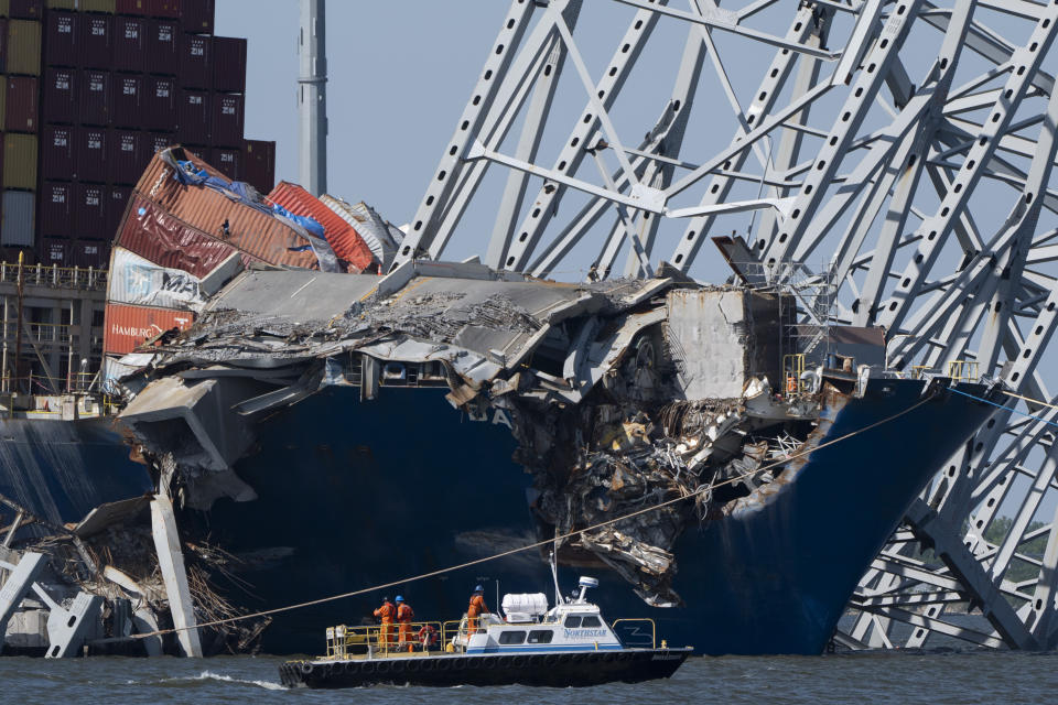 A boat moves past the bow of the container ship Dali prior to the detonation of explosive charges to bring down sections of the collapsed Francis Scott Key Bridge resting on the Dali on Monday, May 13, 2024, in Baltimore. (AP Photo/Mark Schiefelbein)