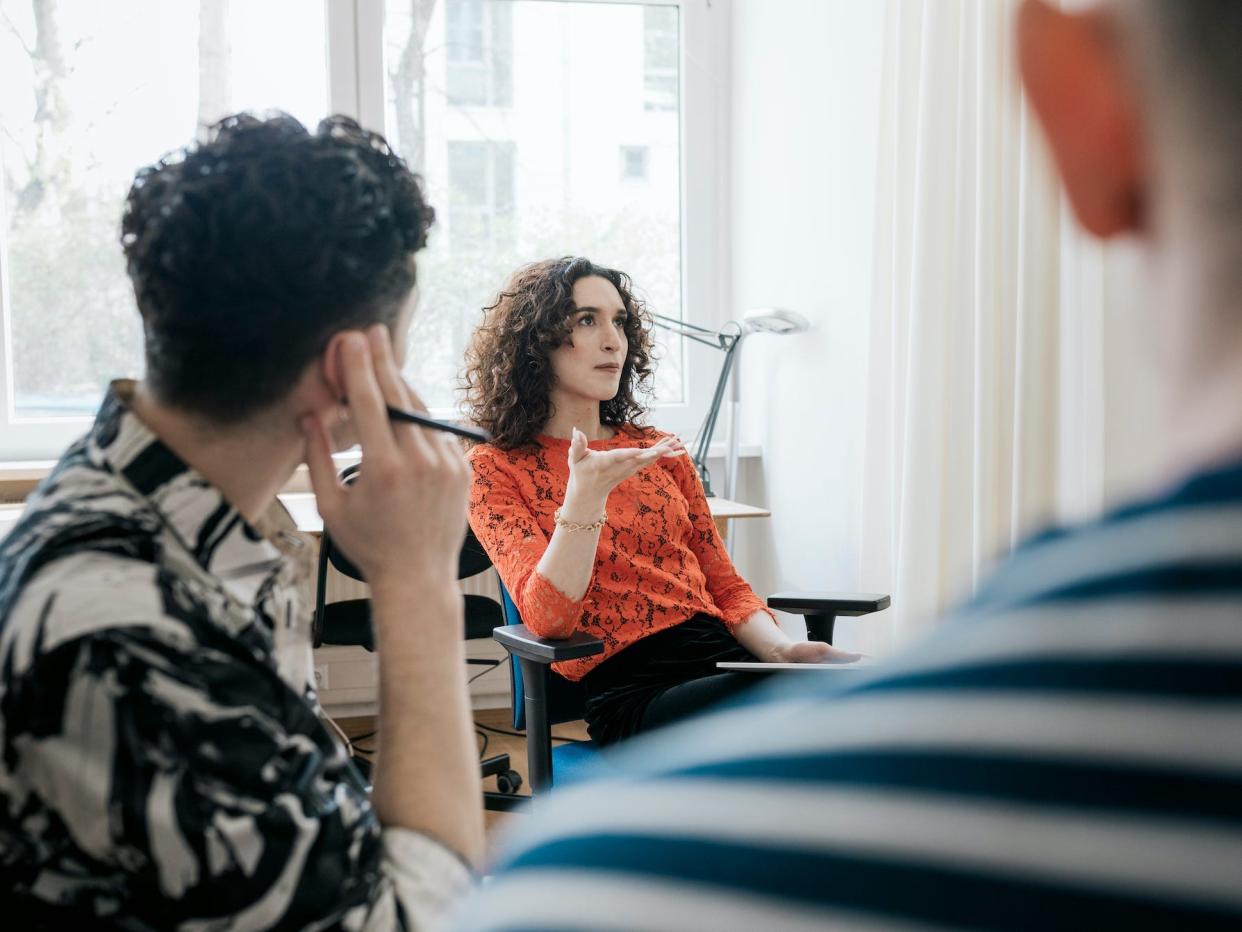 A transgender woman sitting down and talking during a business meeting in the office.