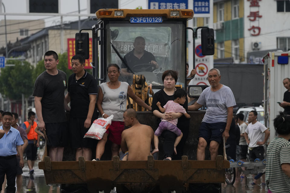 Residents evacuate on a bulldozer in flood-hit Zhuozhou in northern China's Hebei province, south of Beijing, Wednesday, Aug. 2, 2023. China's capital has recorded its heaviest rainfall in at least 140 years over the past few days. Among the hardest hit areas is Zhuozhou, a small city that borders Beijing's southwest. (AP Photo/Andy Wong)