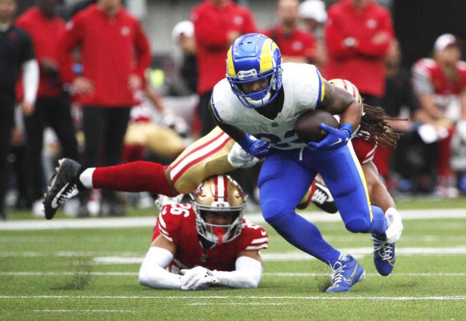 Rams running back Kyren Williams (23) breaks free from the grasp of 49ers linebacker Fred Warner (54).