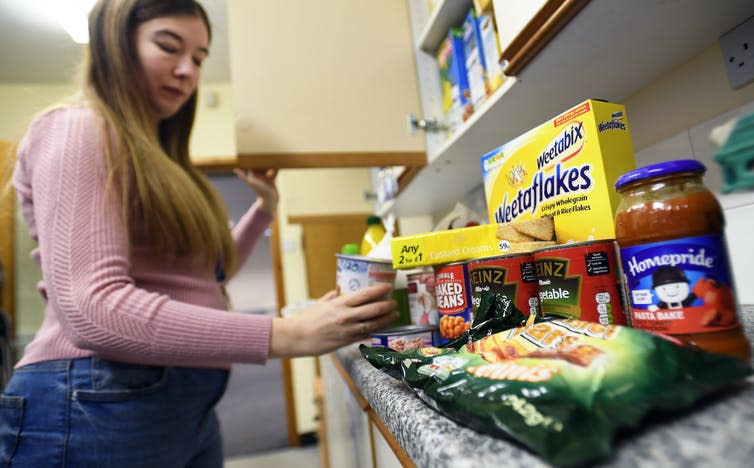 Woman picking up a container from a shelf of food at a food bank