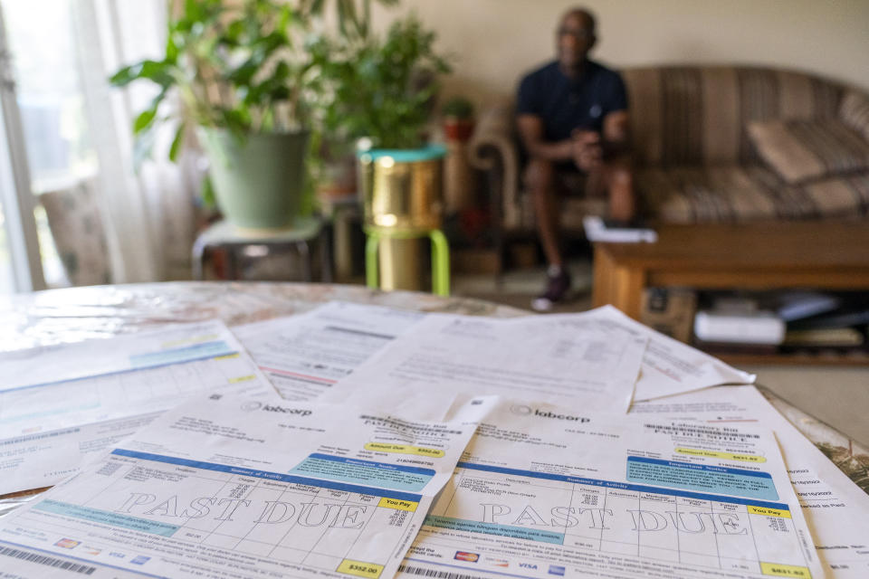 David White, who after kidney surgery got hit with a lot of extra charges, sits for a portrait with some of his medical bill charges in the foreground, at his home in Temple Hills, Md., Monday, June 26, 2023. The Patient Advocate Foundation helped him recoup more than $2,000 he paid for routine lab work. “Every single penny that I paid out was refunded,” said the 61-year-old White, a volunteer foundation board member. “There’s just no way I could figure this out on my own.” (AP Photo/Jacquelyn Martin)