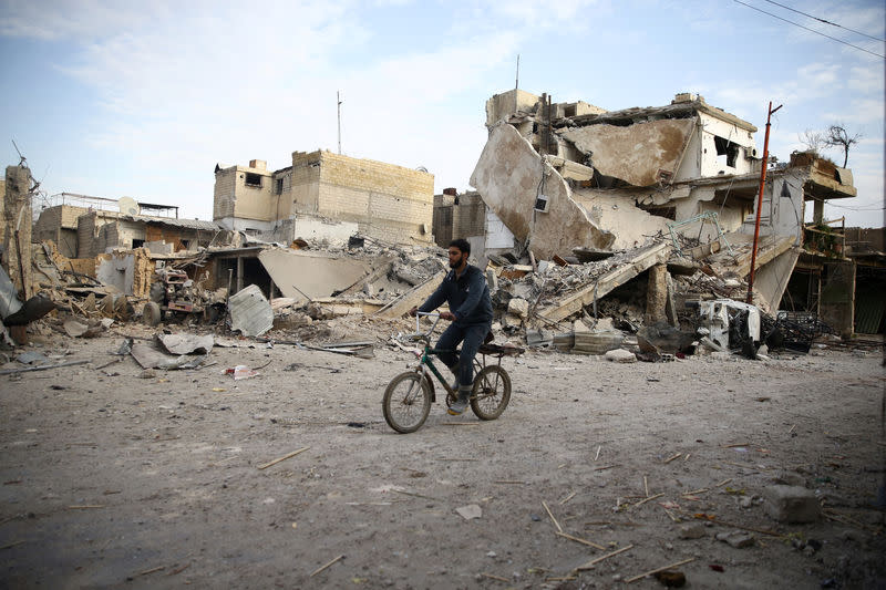 Un jeune homme fait du vélo à Douma, dans la Ghouta orientale, en Syrie. Une dizaine de personnes ont été blessées dans la nuit de mardi à mercredi dans la région de la Ghouta orientale, près de Damas, après deux jours de bombardements intensifs des forces gouvernementales syriennes qui ont fait au moins 250 morts. /Photo prise le 20 février 2018/REUTERS/Bassam Khabieh