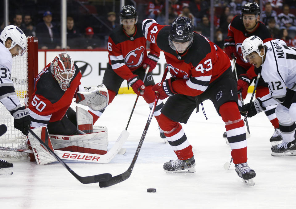 New Jersey Devils defenseman Luke Hughes (43) clears the puck away from goalie Nico Daws (50) during the first period of the team's NHL hockey game against the Los Angeles Kings on Thursday, Feb. 15, 2024, in Newark, N.J. (AP Photo/John Munson)