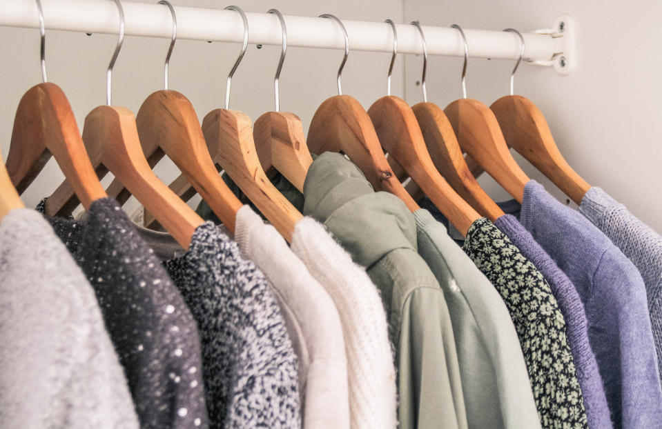 A stock image of several sweaters hanging in a closet