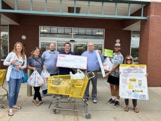 Central Elementary staff members pose with their check, shopping cart of supplies, and OfficeMax managers.